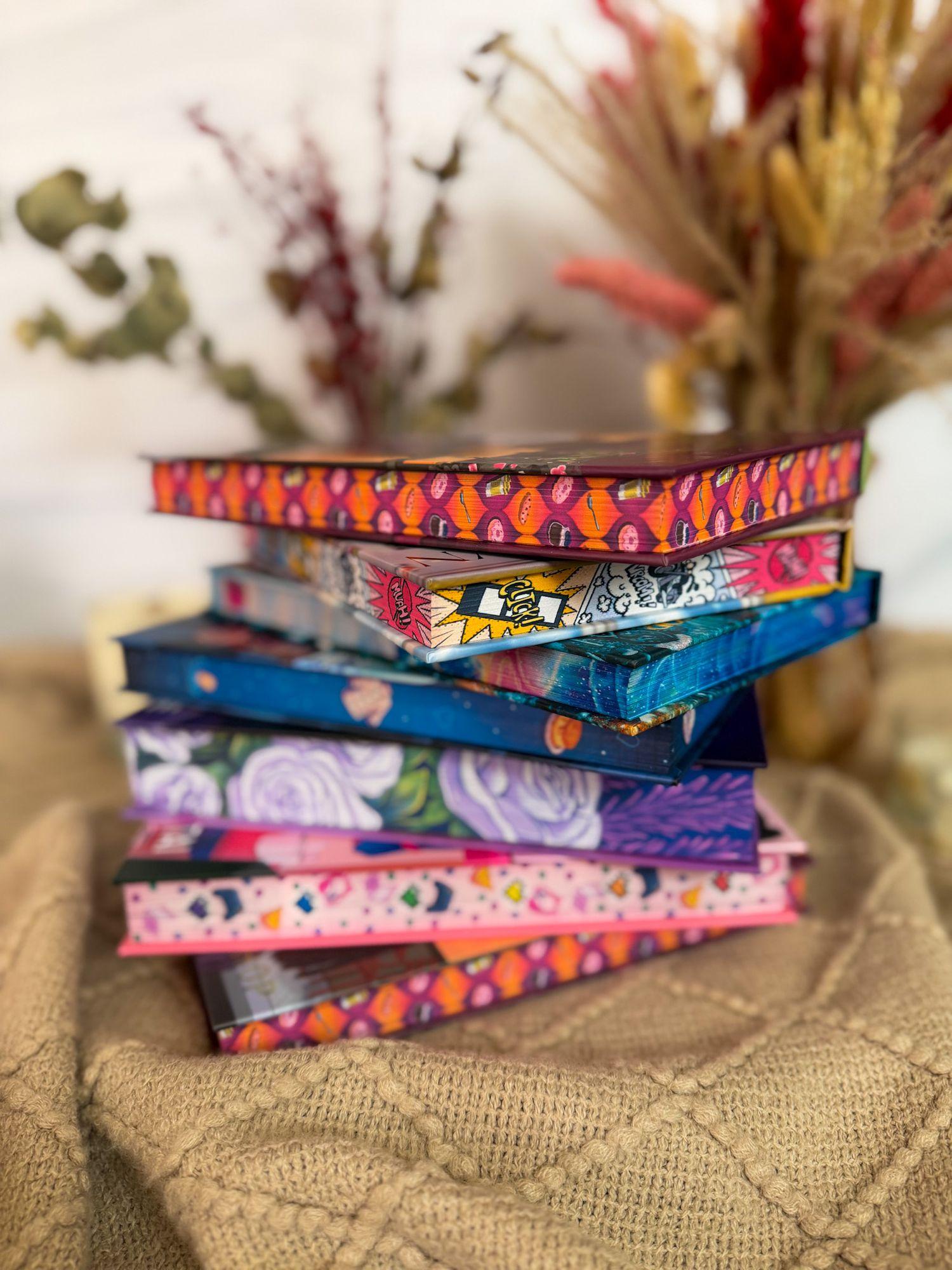 A stack of Cover Snob editions displaying colorful custom-designed sprayed edges